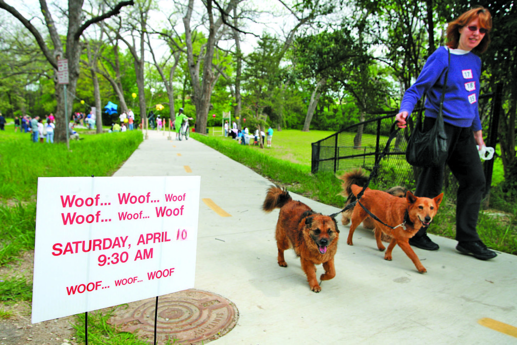 Deborah Carpenter walks Jenny, Buster, and Lily past a sign for the second annual East Kessler Pet Parade along Coombs Creek Trail in April 2010. Photo: Christina Barany, for Oak Cliff People