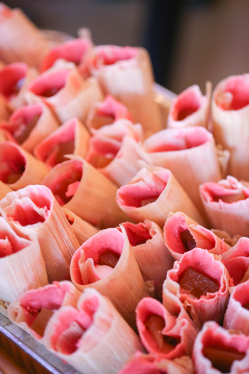 These are guava dessert tamales.  Traditionally, red food coloring is added to the masa to give them their pink hue. 