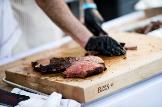 A chef slicing steak on a wood cutting board at Chefs for Farmers.