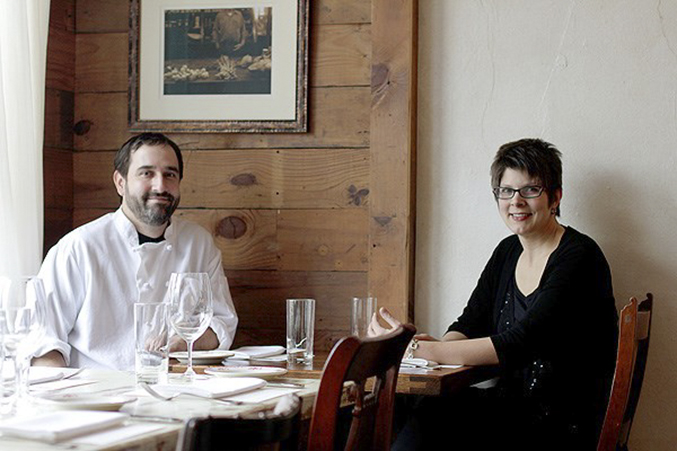 Jennifer and David Uygur, the owners of the restaurant Lucia, sitting inside the dining room at a table.
