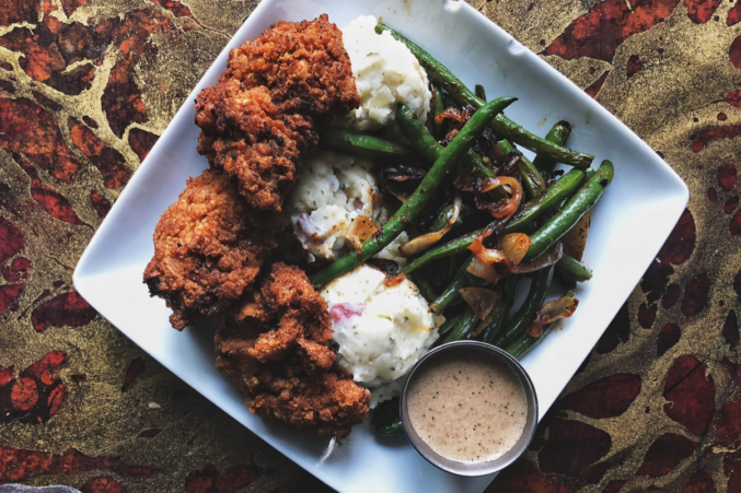 A plate of vegan chicken freid steak with mashed potatoes and green beans.