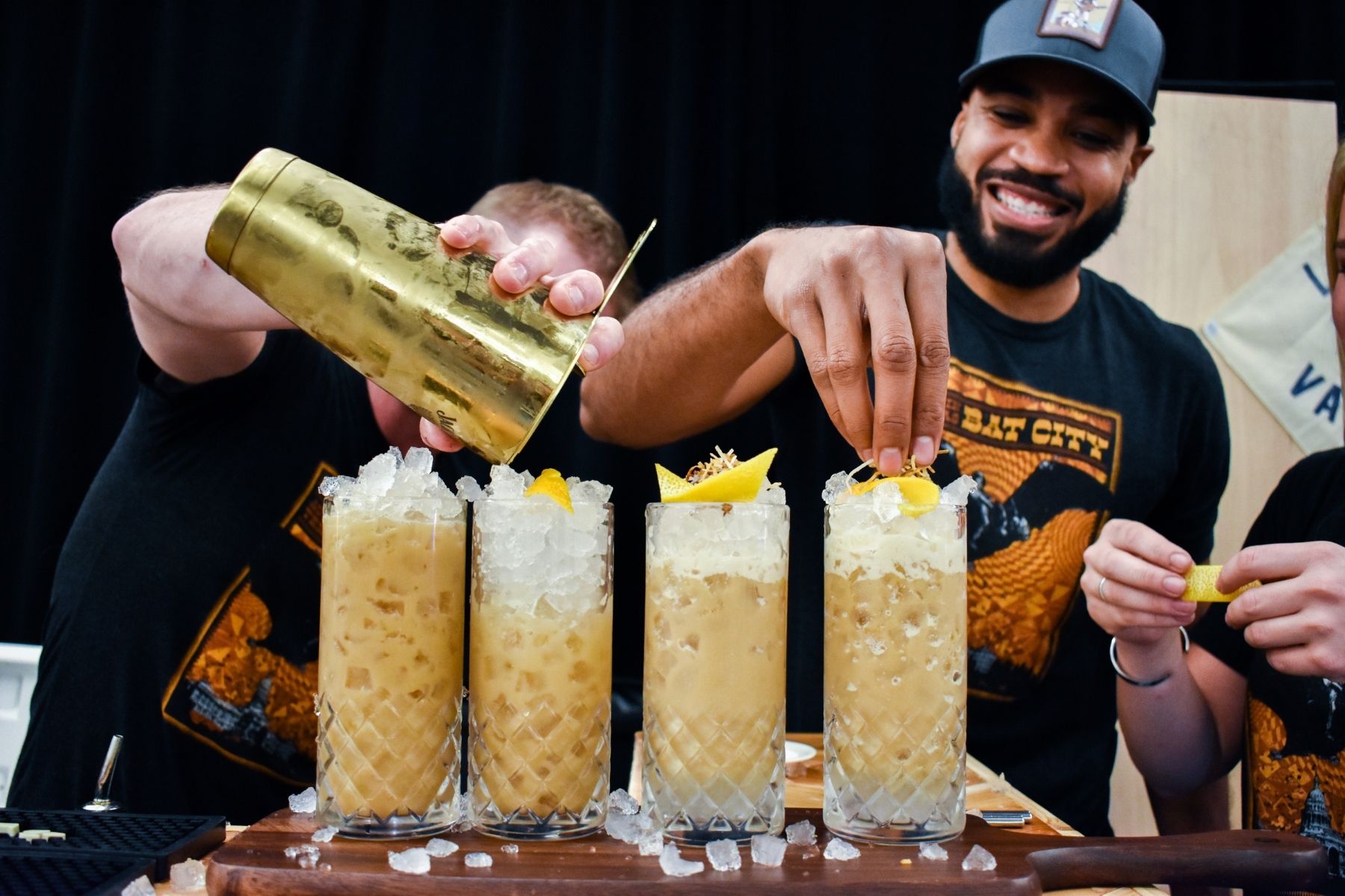 Bartenders making what appears to be a tiki-style cocktail for an Austin Food & Wine Alliance food festival.