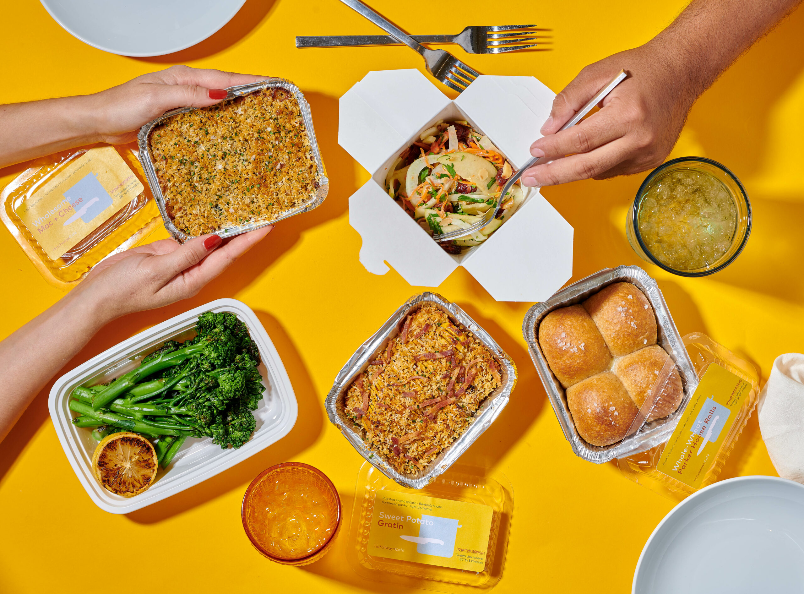 Takeout containers with bread rolls, broccoli, vegetables, and more.