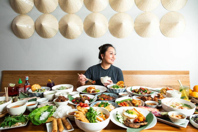 Ngon Vietnamese Kitchen owner, chef Carol Nguyen, at a table with a huge variety of dishes.