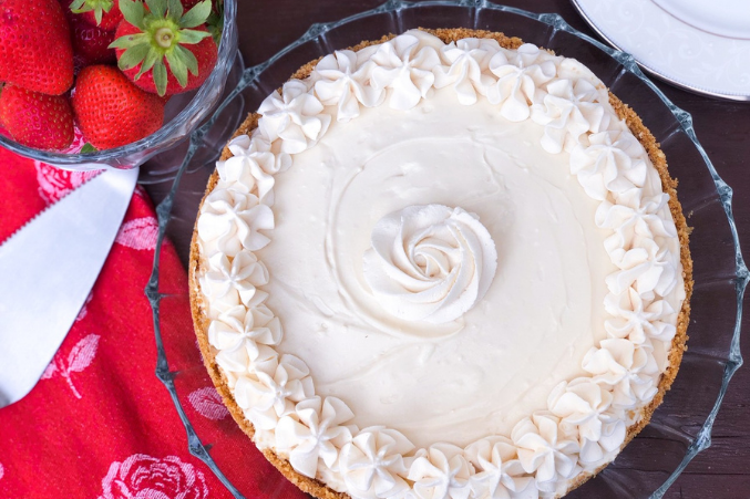 A big vanilla cheesecake with swirly frosting.