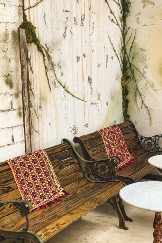 A little corner of the Yellow Rosa bar with plant greenery and rustic-style benches.