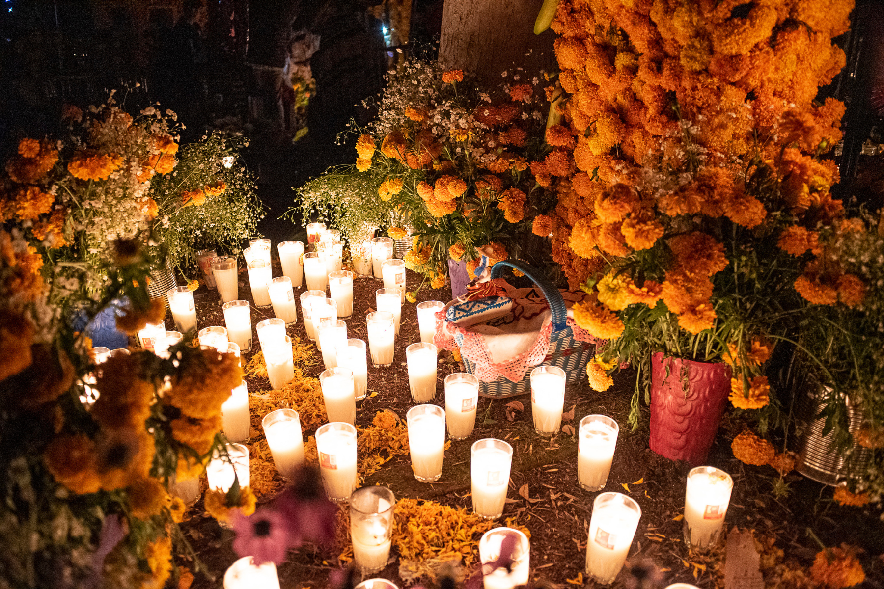 An altar, or ofrenda, for Dia de los Muertos with candles, sugar skulls, and orange flowers.