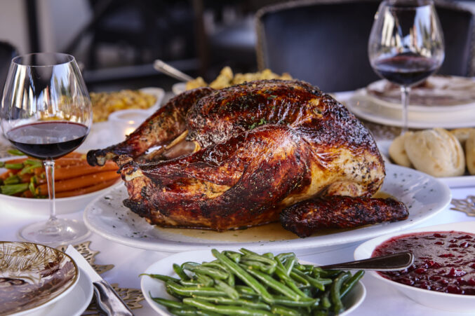 A dark brown roasted turkey with sides on a table.