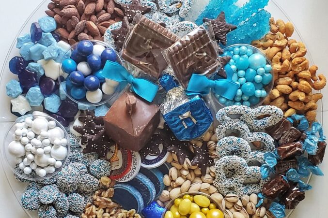 A Hanukkah board with choclate treats, candies, and macarons.