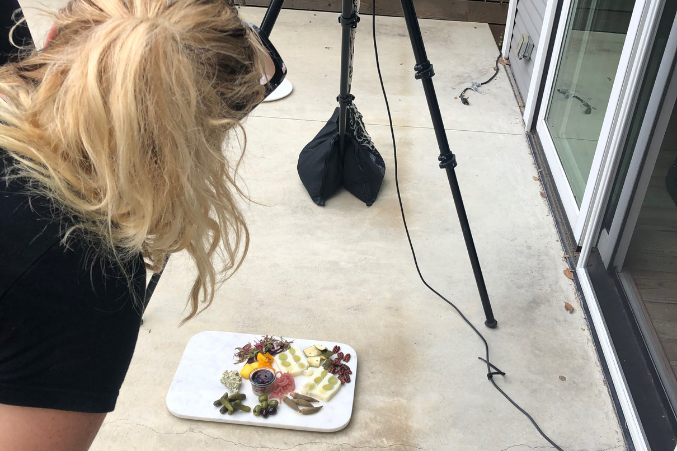 Elizabeth Lavin shooting a platter of charcuterie on the ground for the Best Bites of Dallas December 2020 issue.