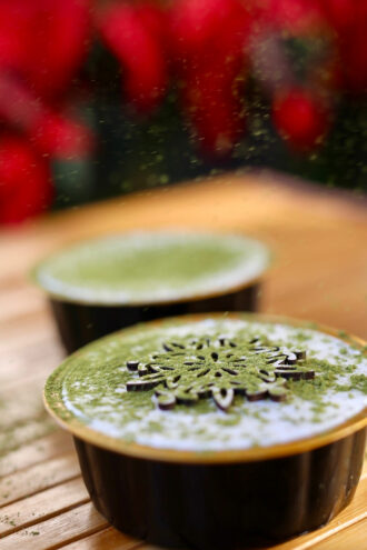 A cup of parfait with a snowflake decal on top, and a dusting of matcha powder.