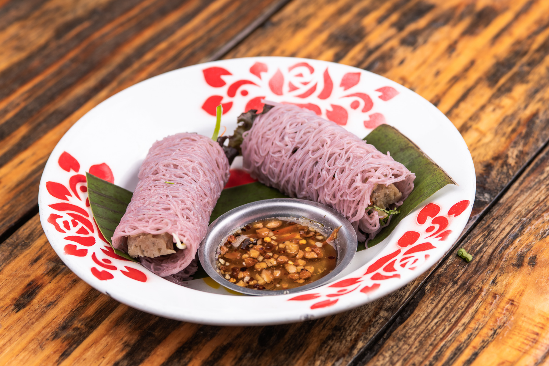 Purple-tinted rice noodles wrapped around a filling.