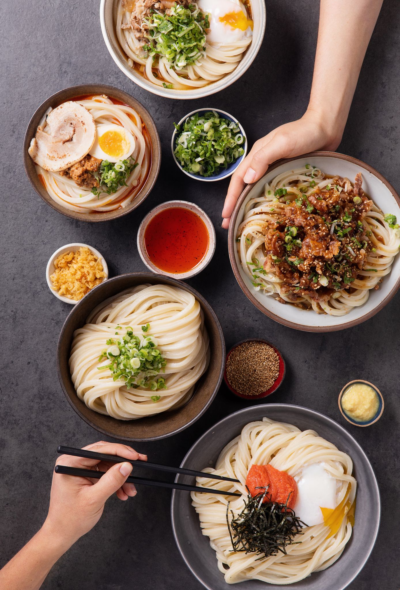 Bowls of udon noodles, soup, and sides.