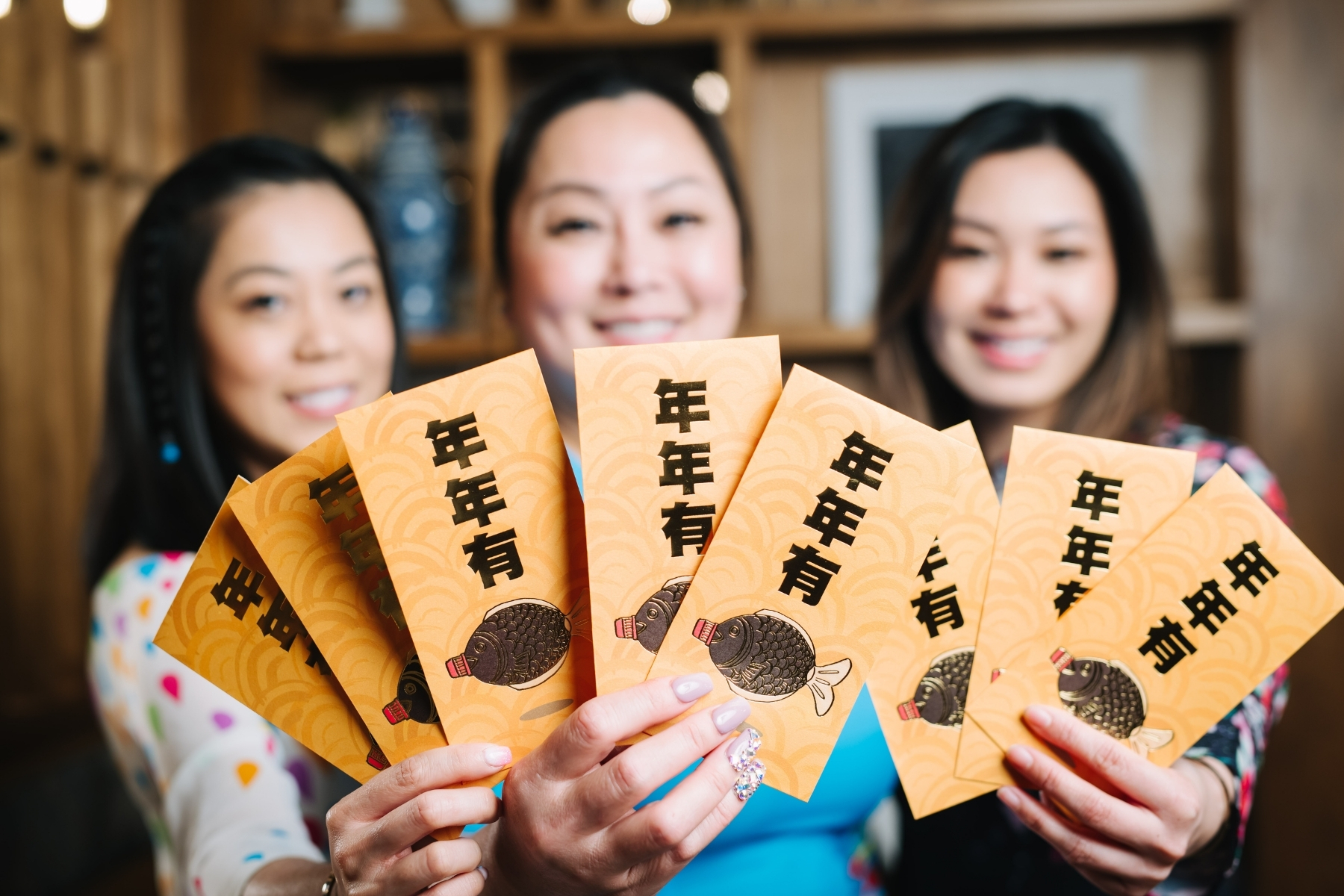 Three women holding lucky envelopes.