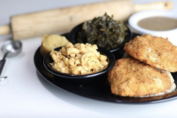 A plate of vegan food: vegan mac and cheese, collard greens, seitan/meat-free 