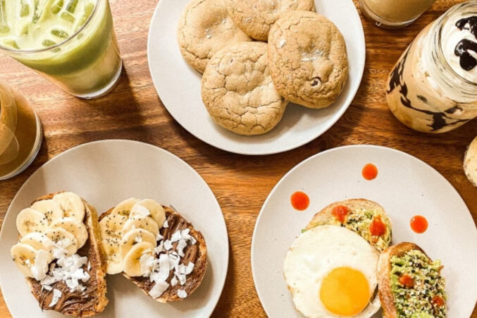 An array of coffee shop pastries, toasts with avocado and fried egg, plus iced coffee drinks.