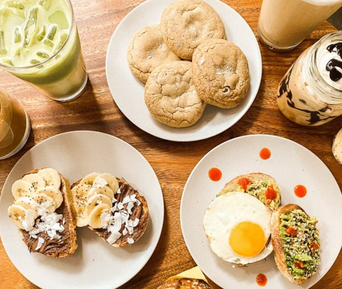 An array of coffee shop pastries, toasts with avocado and fried egg, plus iced coffee drinks.