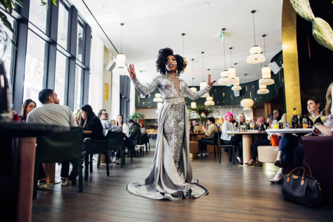 A drag queen in a silver mermaid-silhouette dress.