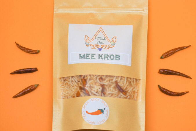On an orange background, there's a package of Thai Mee krob, which is crispy, deep-fried rice noodles.