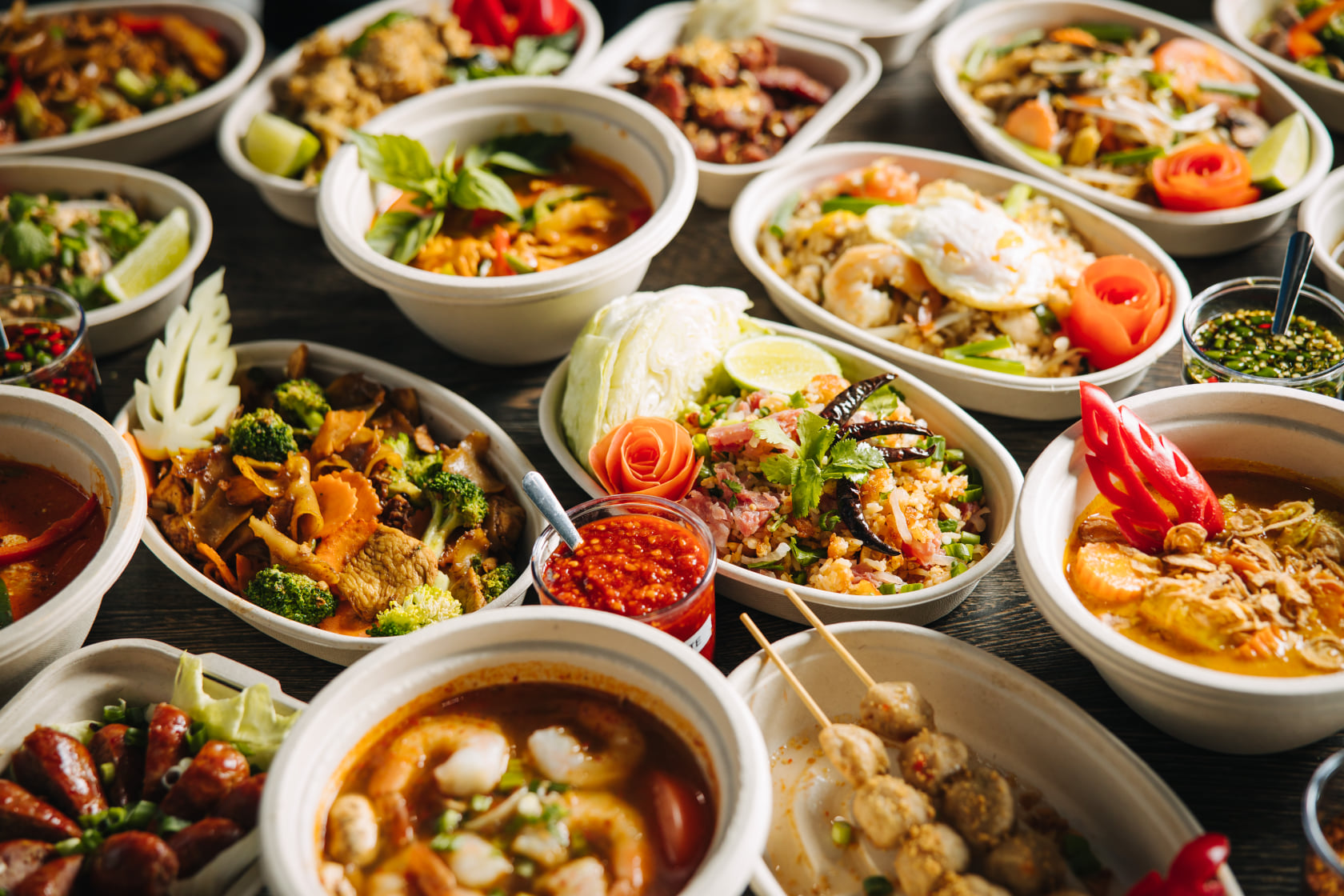 A table filled with bowls of Lao and Thai food, from beef skewers to pork sausages and curries to larb.