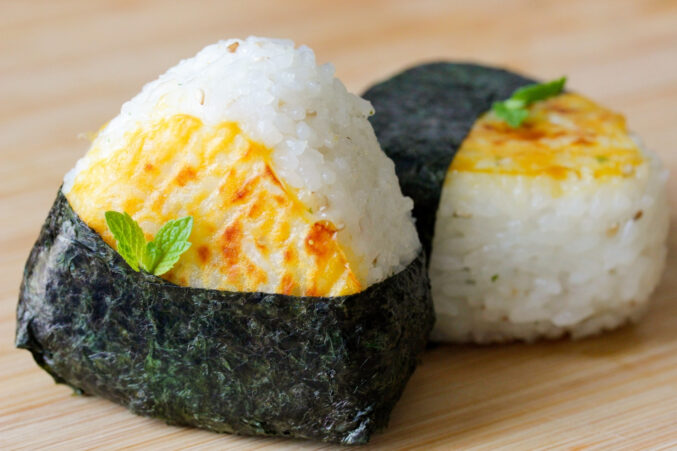 Two triangle-shaped onigiri rice balls wrapped in seaweed.