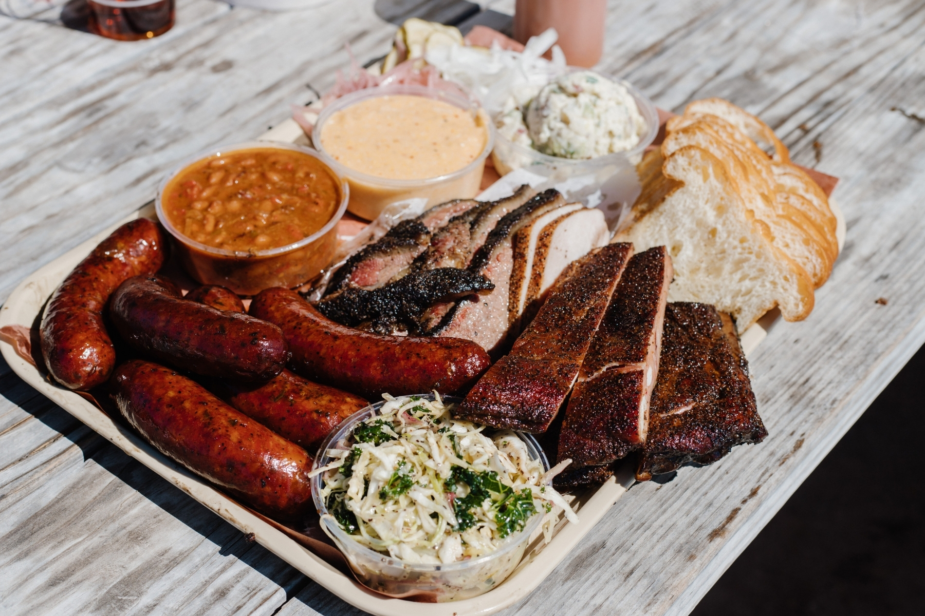 A packed tray of barbecue (ribs, links, beans, mac, slaw, bread) from Goldee's Barbecue