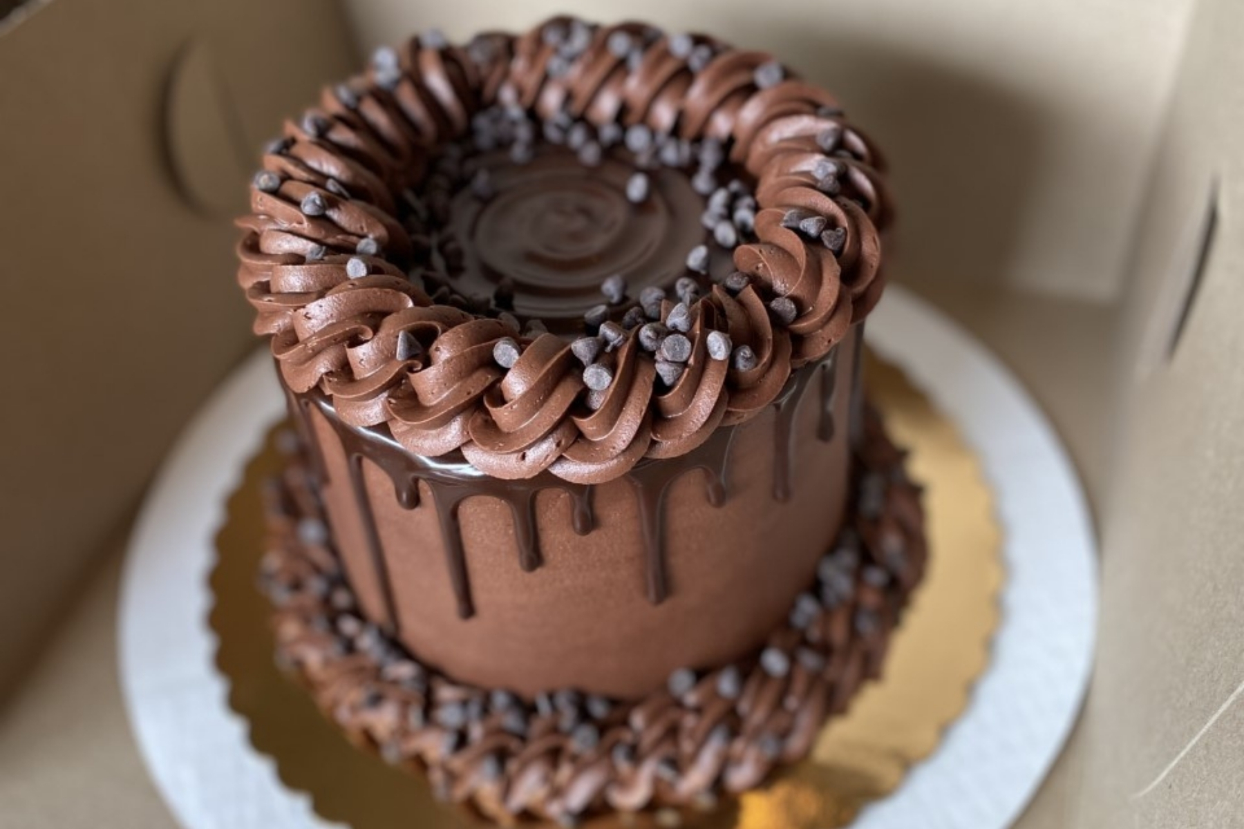 A tall chocolate cake with swirls of frosting and chocolate drizzle.