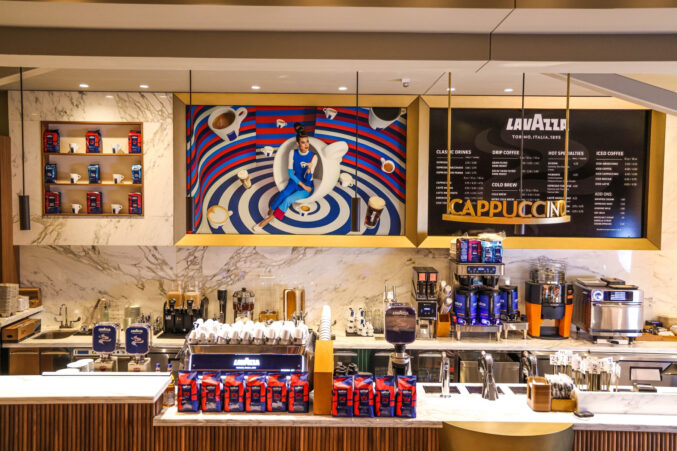 An espresso bar with coffee beans, an espresso machine, and a menu of coffee drinks in the background.