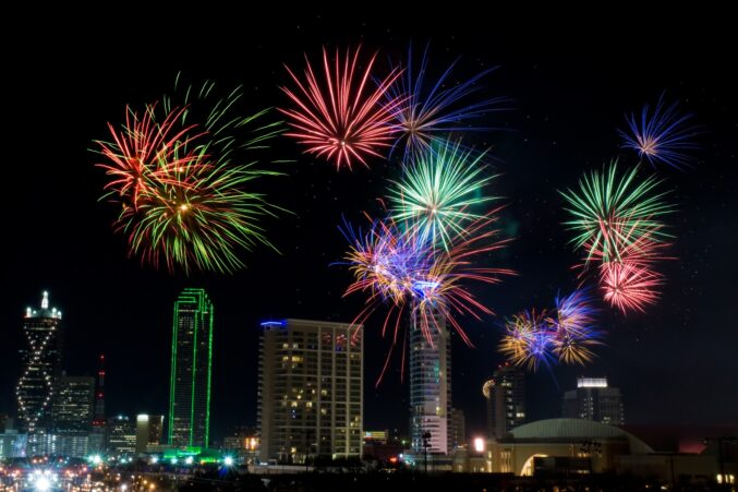 Fireworks at night in front of the Dallas skyline.