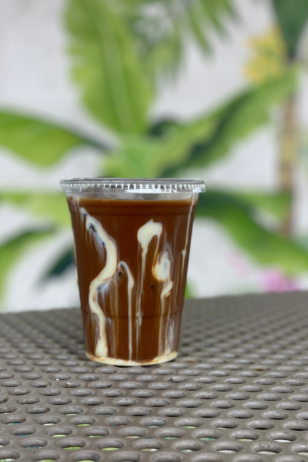 A cup of Vietnamese coffee called cafe sua da made with coconut cream and sweetened condensed milk, which is placed on a outdoor patio table.