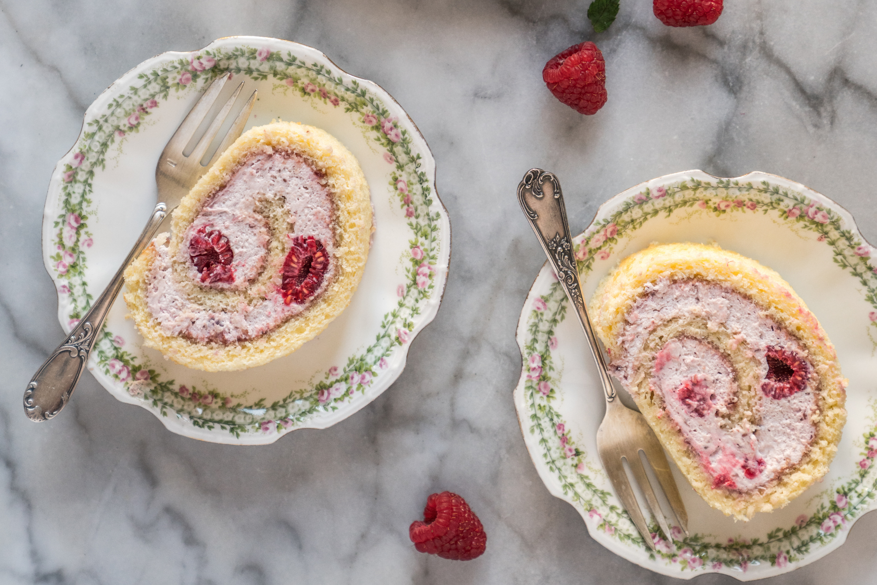 rolled raspberry on twee plates on a marble tabletop