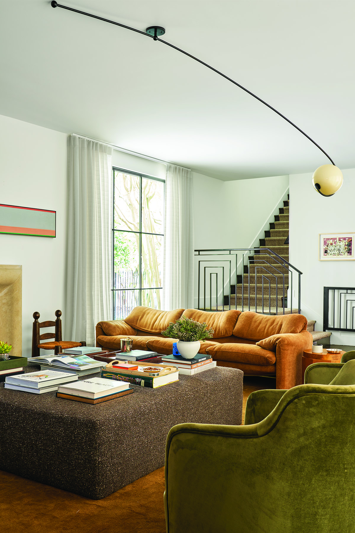 The living room space with cozy couches and metal staircase behind living room couch.