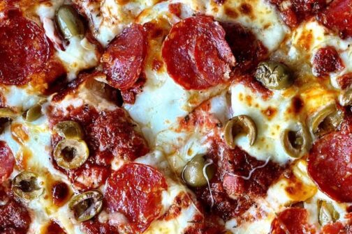 Close-up shot of a pepperoni and olive Detroit-style pizza.