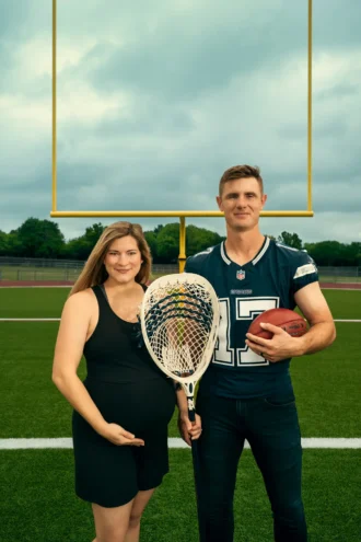 Jenn and Brandon Aubrey pose on a football field in front of a goalpost. They are holding a lacrosse stick between them, and the man is also holding a football under his arm.